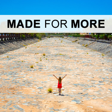 A made for more girl standing in dry river bed with hands raised up